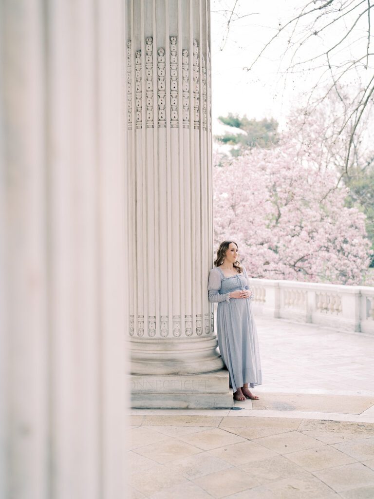 Pregnant Mother In Light Blue Dress Leans Against Column At The Dar Constitution Hall.