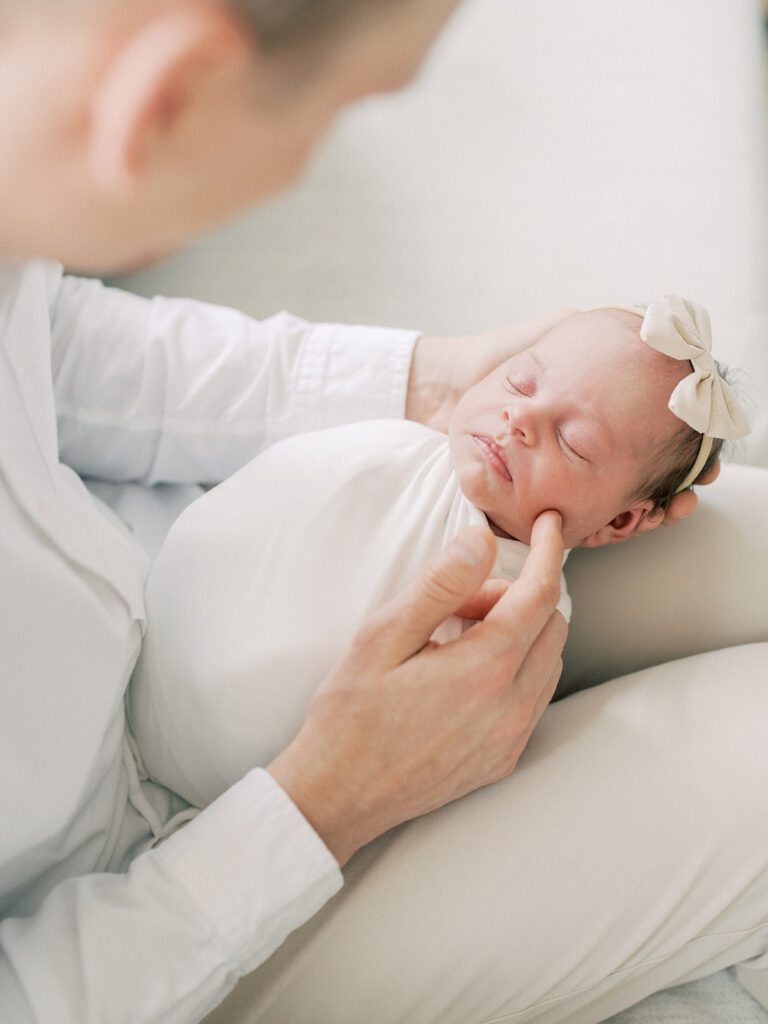 A Father Caresses His Newborn With A Finger.