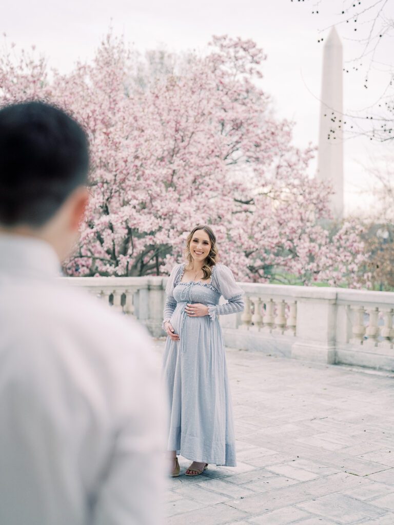 Pregnant Woman In Light Blue Dress Smiles At Her Husband While Standing On The Balcony Of The Dar Constitution Hall During The Dc Magnolias Bloom.