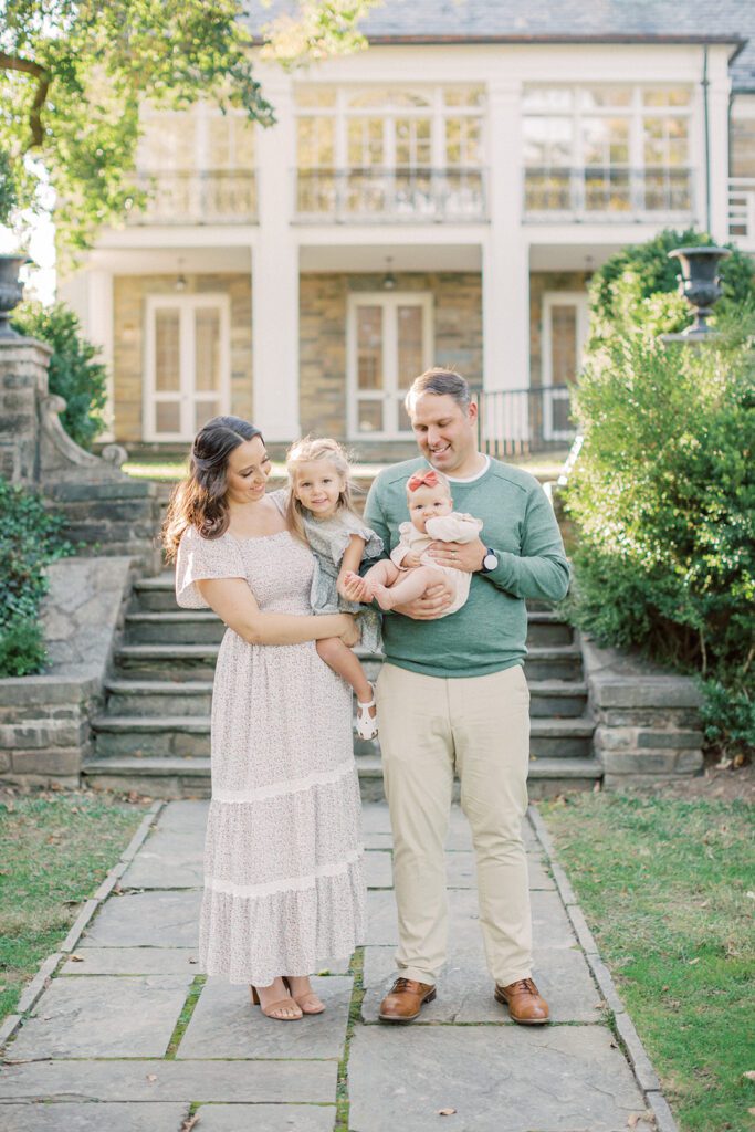 Family of four smiles during their family photo session at Glenview Mansion in Rockville.