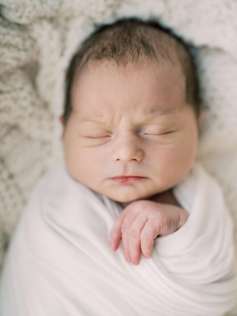 A Baby Swaddled In White Sleeps Peacefully, Photographed By Bethesda Newborn Photographer Marie Elizabeth Photography.