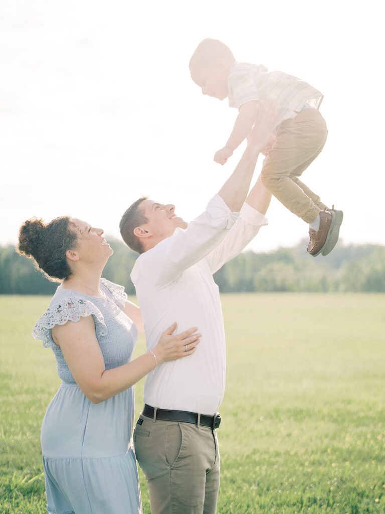 Father Throws His Toddler Son In The Air As Mother Stands With Them, Photographed By Manassas Photographer Marie Elizabeth Photography.