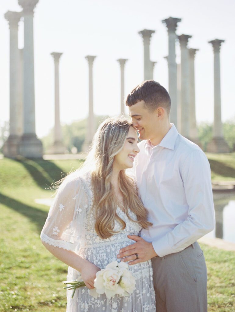 Couple Stand In Front Of The Capital Columns At The National Arboretum For Their Maternity Session.