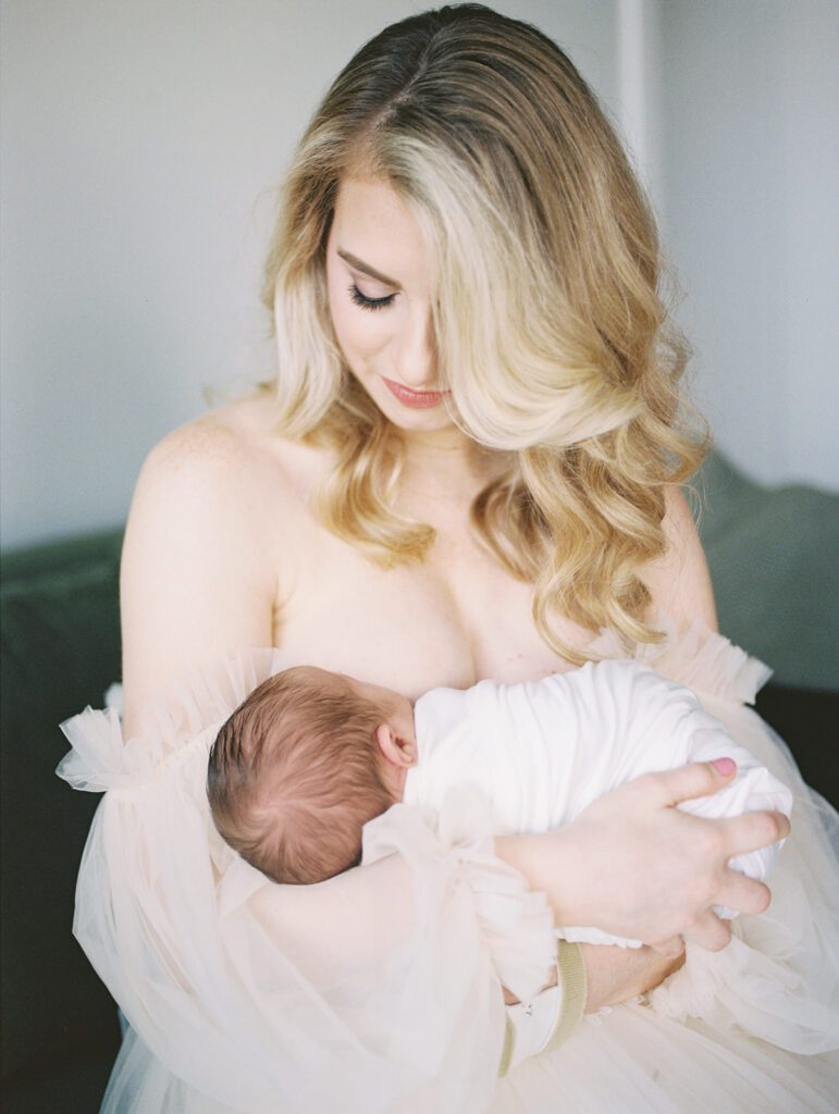 A Blonde Mother Sits Nursing Her Son.