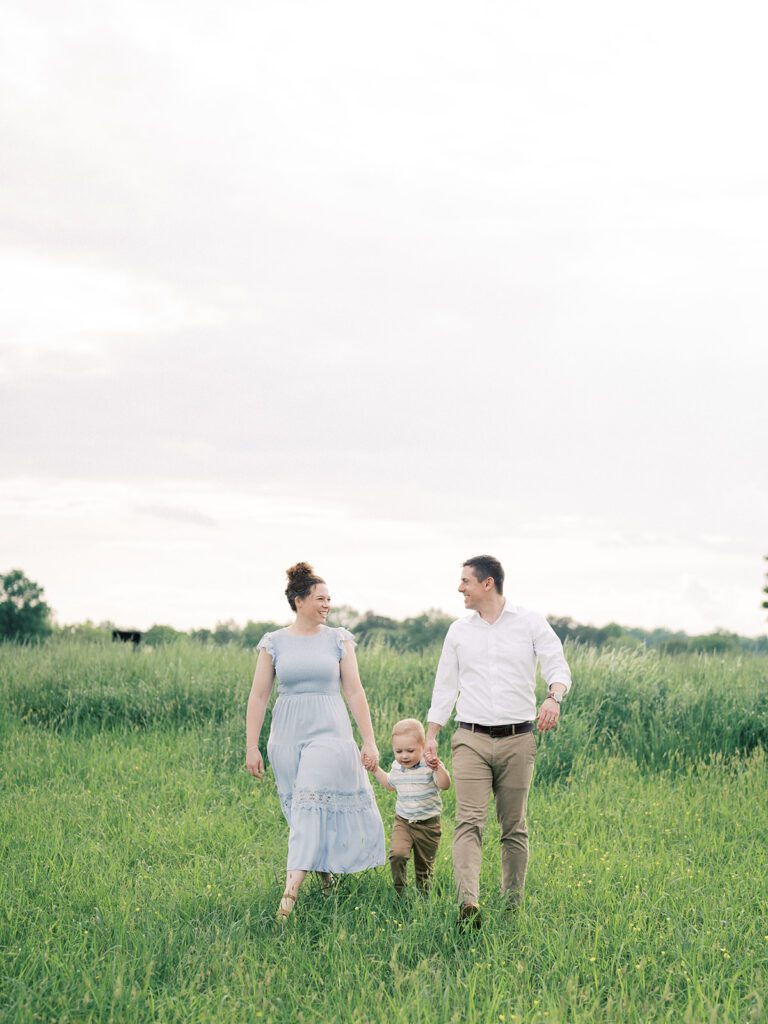 Mother And Father Walk Through A Field With Their Son, Photographed By Manassas Photographer Marie Elizabeth Photography.