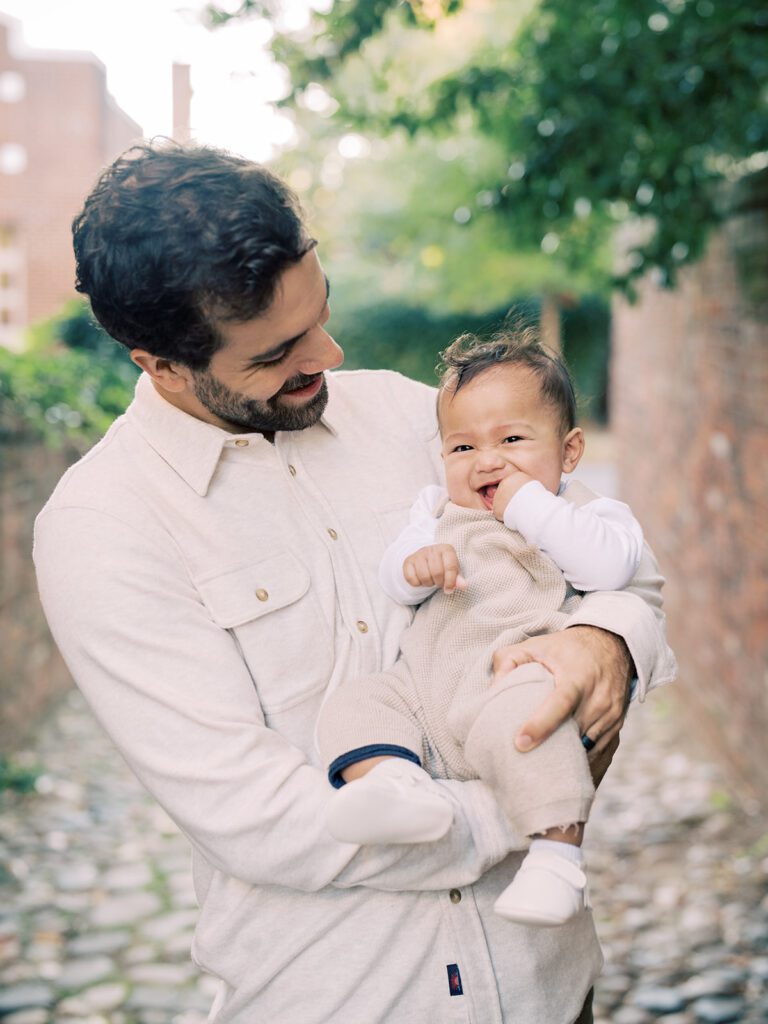 A father holds his baby boy while standing in an alley in Old Town Alexandria.