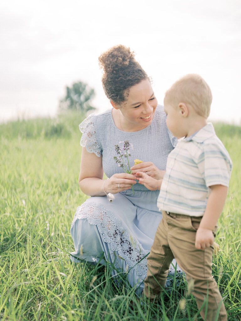 A Mother In A Blue Dress Kneels Down As Her Son Gives Her Flowers, Photographed By Manassas Photographer Marie Elizabeth Photography.