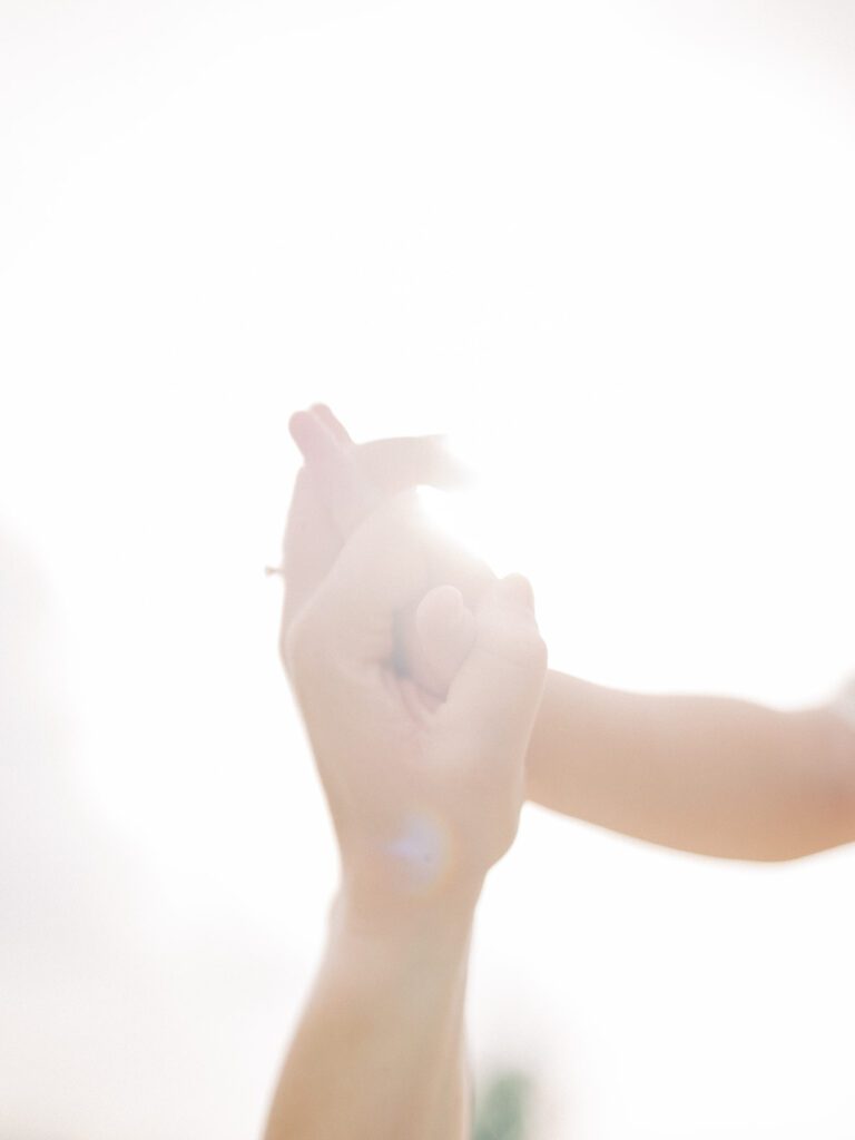 Close-Up View Of Hands Intertwined Backlit With The Sun.