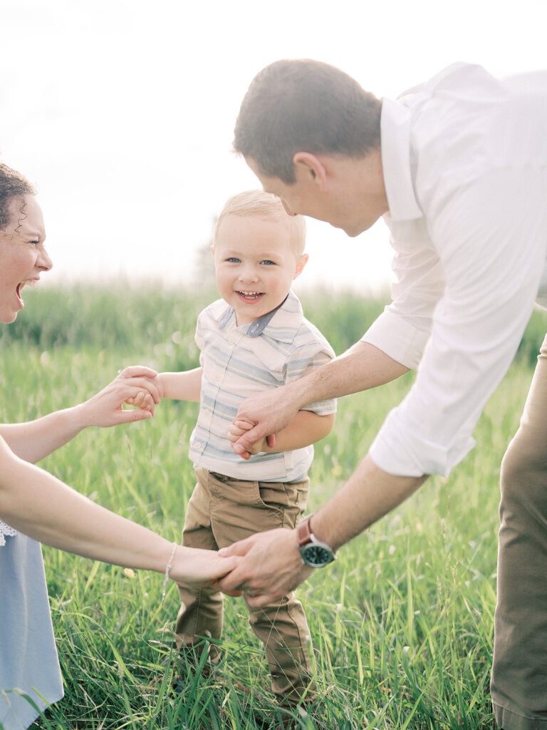 Little Boy Smiles At The Camera As His Parents Kneel Down With Him In Manassas Battlefield.