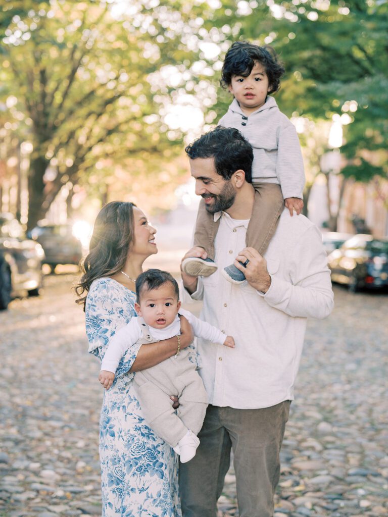 A mother and father hold their two young boys on Prince St. in Old Town Alexandria, photographed by Alexandria Photographer, Marie Elizabeth Photography.