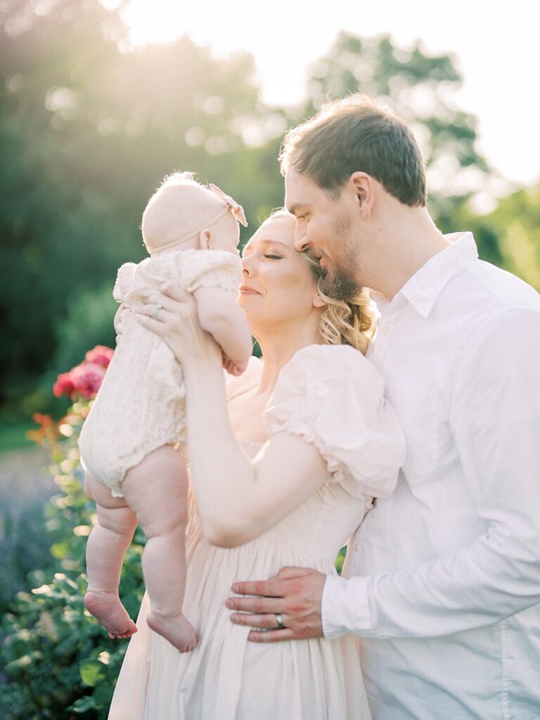 A Mother And Father Hold Their Baby Up To Their Face To Cuddle During Their Arlington Family Photos.