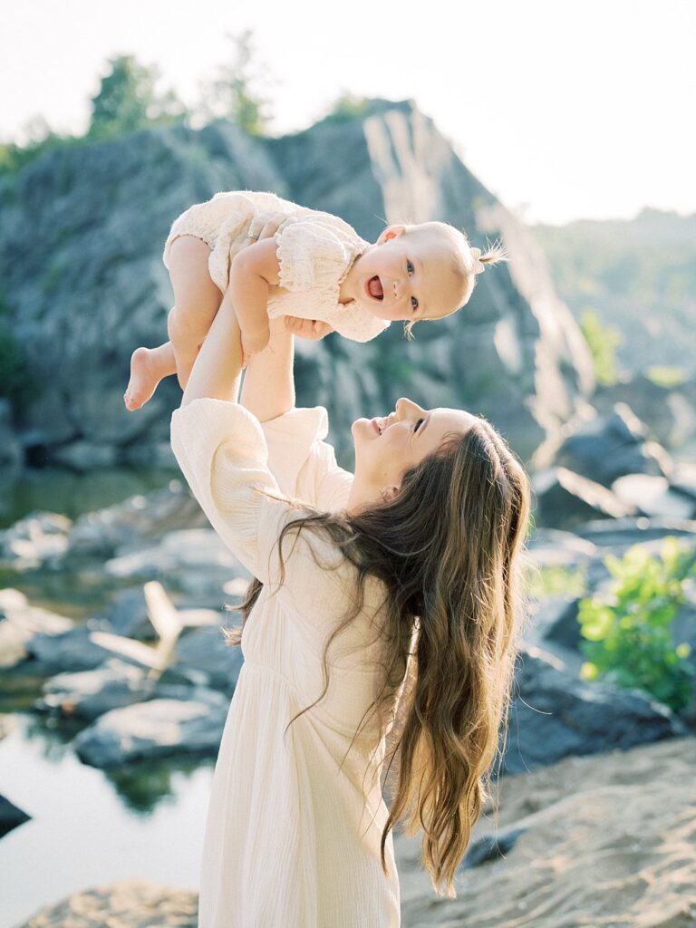 A Mother With Long Brow Hair Holds Up Her One Year Old Daughter During Their Great Falls Park Photos.