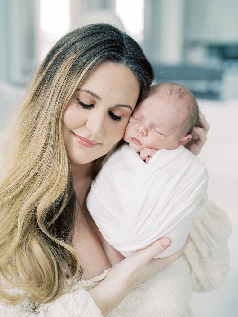 A Mother With Long Hair Holds Her Baby Up To Her Face During Their Olney Newborn Photos.