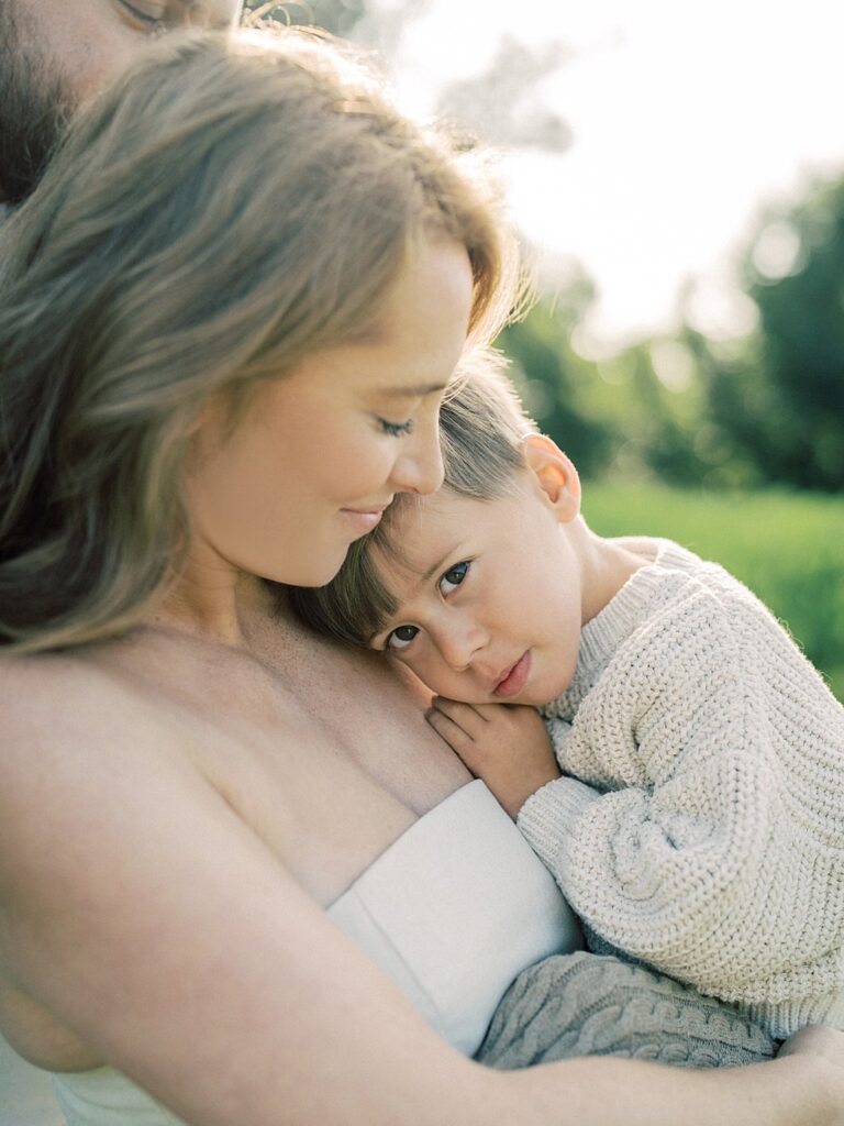 Little Boy With Big Brown Eyes Looks At The Camera While He Is Held By His Mother, Photographed By One Of The Best Rockville Md Family Photographers, Marie Elizabeth Photography.