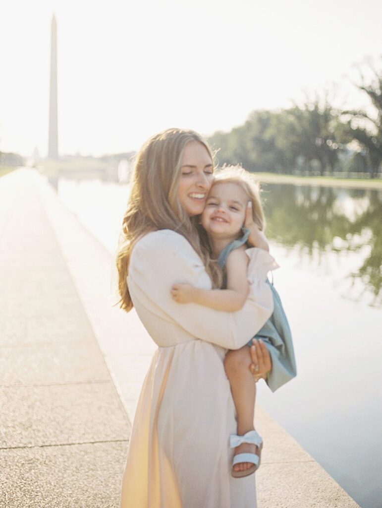 A Mother Holds Her Daughter Close While Standing By The Reflecting Pool In Dc.