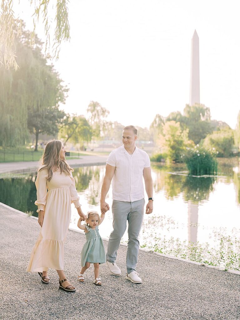 A Father And Mother Walk With Their Little Girl During Their Constitution Gardens Family Photos.