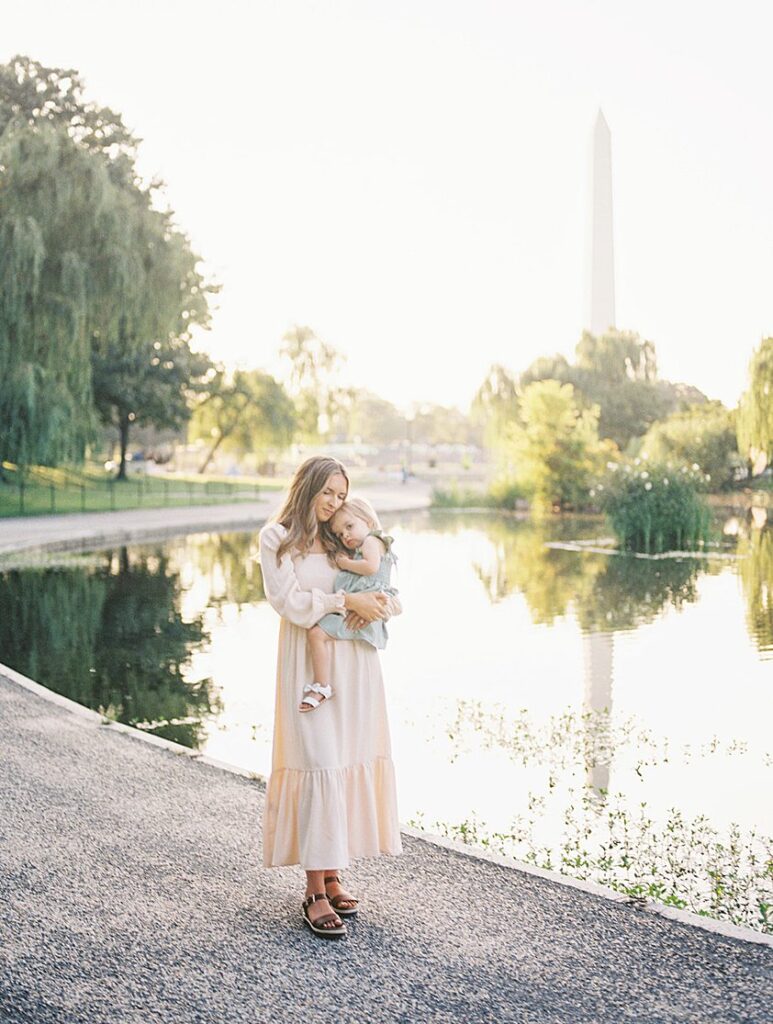 A Mother Holds Her Little Girl By The Water At Constitution Gardens In Dc.