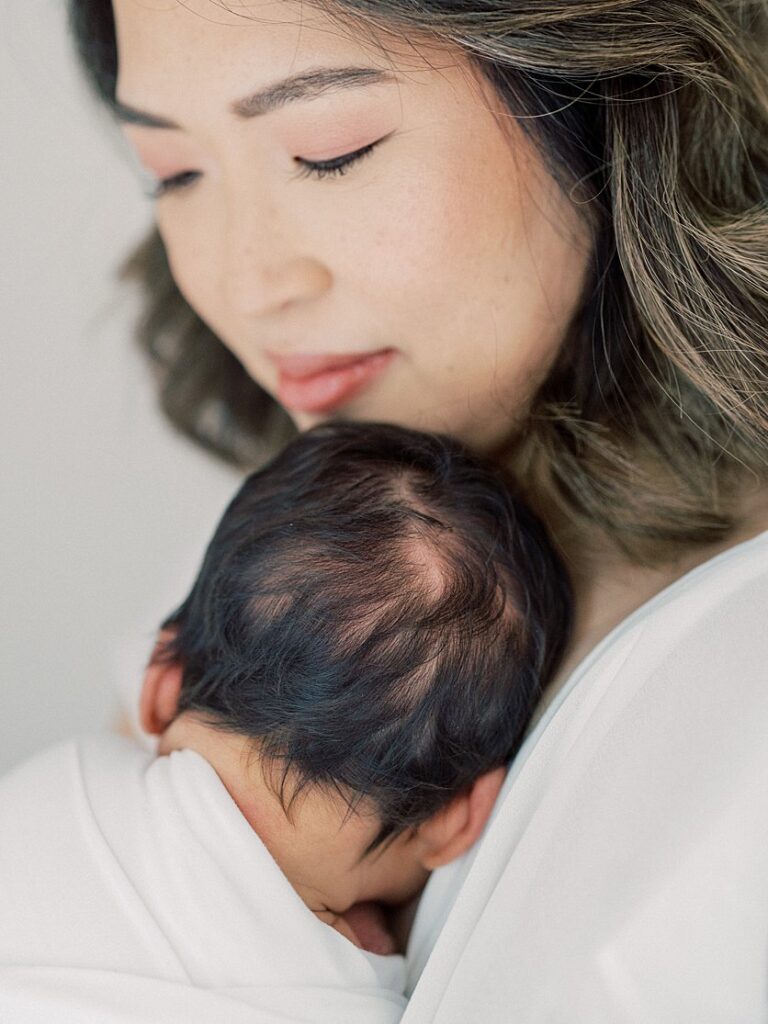 Close-Up View Of Newborn Baby's Black Hair As Baby Rests Against Mother's Chest.