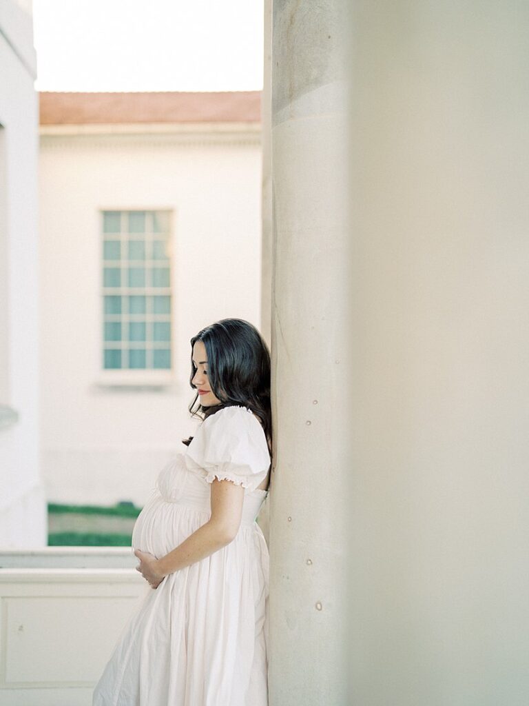 A Pregnant Mother Leans Against A Pillar During Her Maryland Maternity Photos.