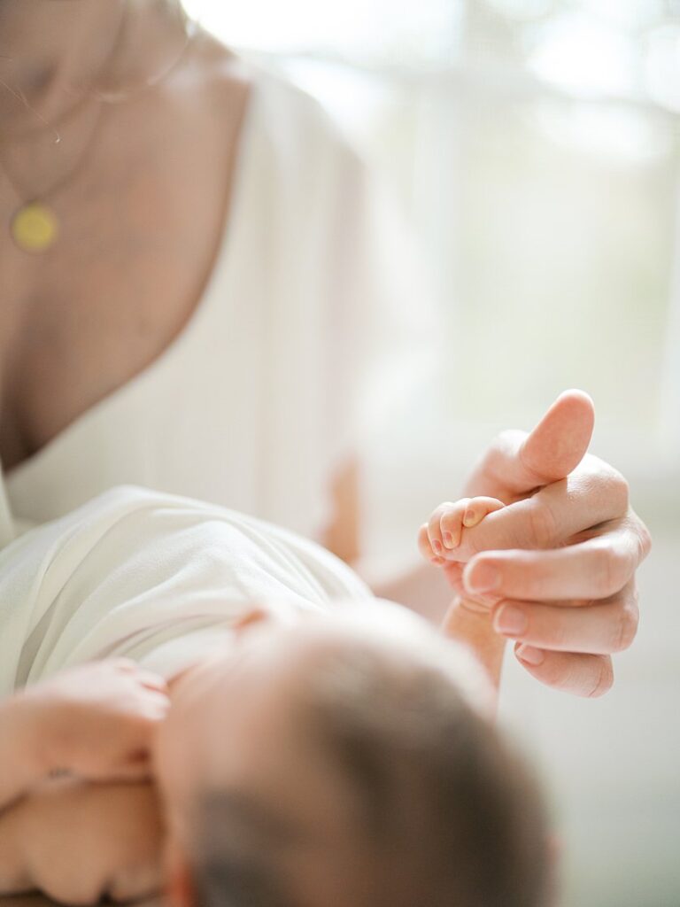 Mother Holds Baby's Hand Around Her Finger.