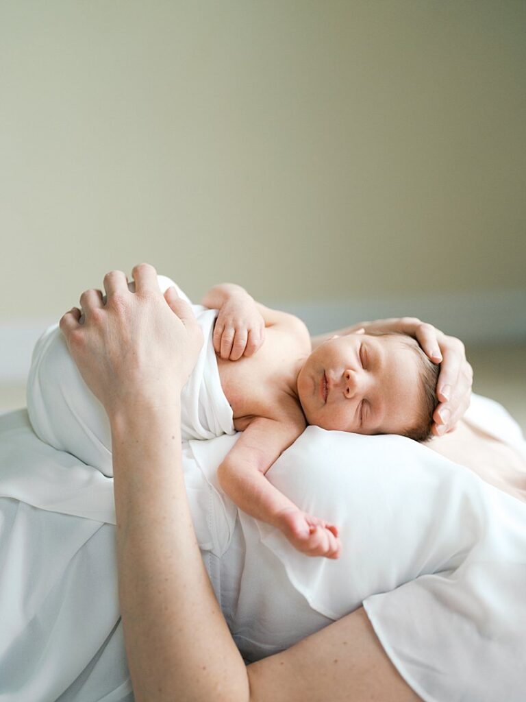 A Baby. Sleeps On His Mother's Chest As She Lays On The Ground During Their Newborn Session In Rockville, Maryland.