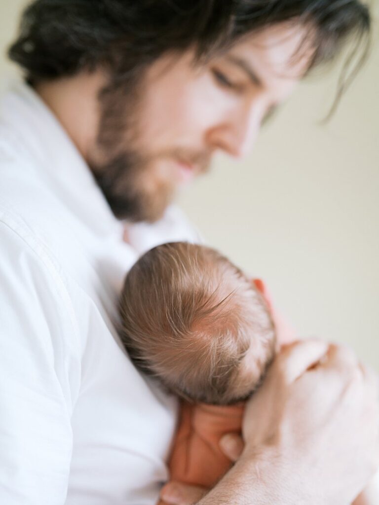 Close Up View Of A Newborn Baby's Hair As He Sleeps On His Father.