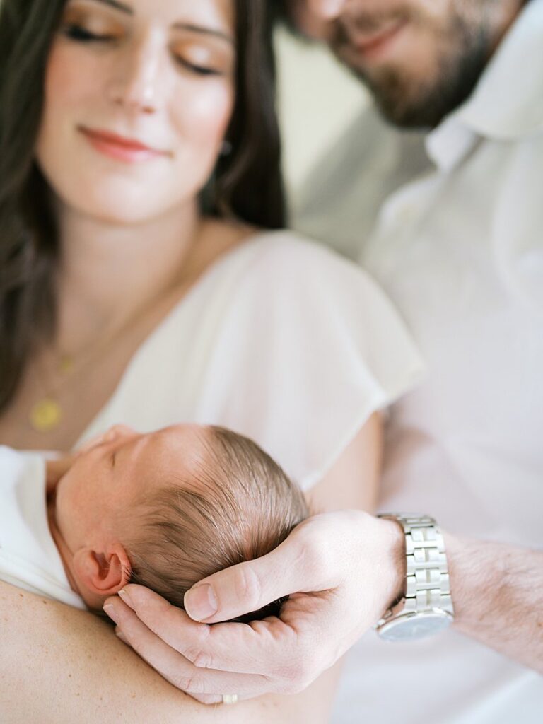 Close-Up View Of A Newborn Baby Held By His Father And Mother.