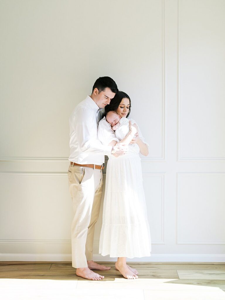 New Parents Cuddle Close Against A Wall During Their Severna Park Newborn Photos.