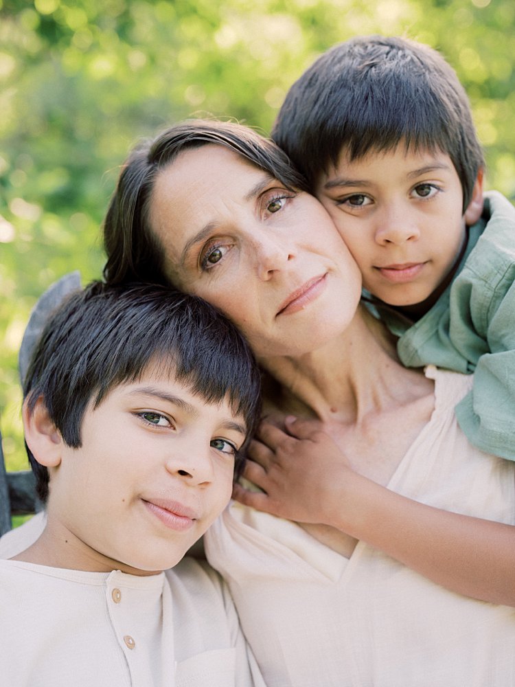 Mother And Two Sons Sit Head-To-Head While Looking At The Camera.