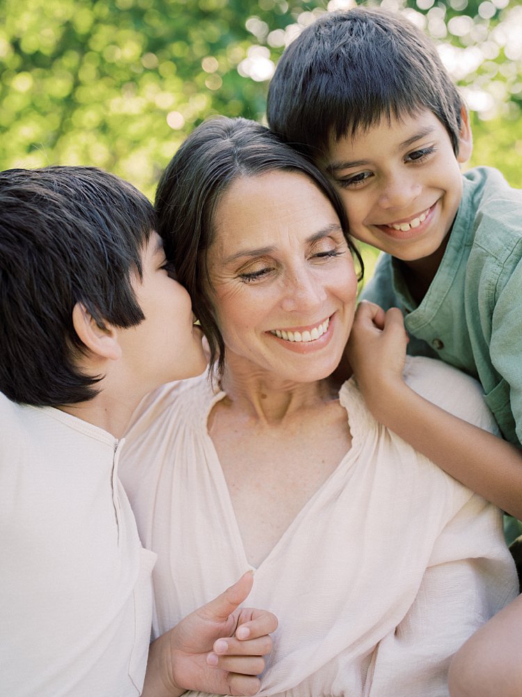 A Mother Smiles As Her Boys Giggle In Her Ears During Their Great Falls Family Photos.