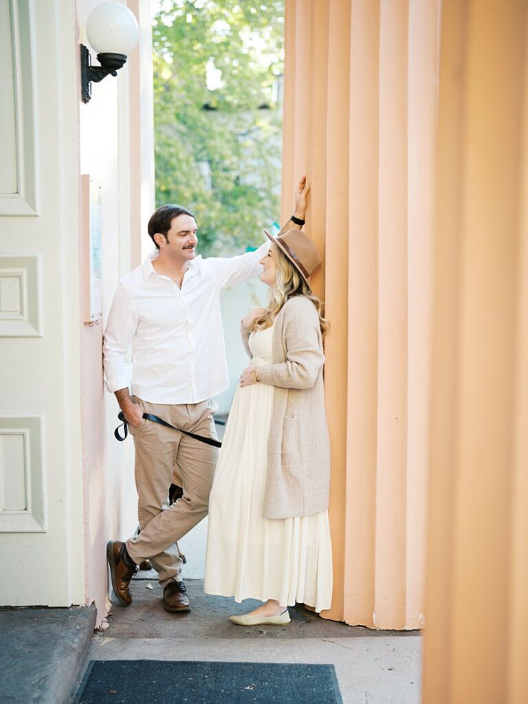 A Couple Stands Amongst Pink Columns In Old Town Alexandria During Their Maternity Photos.