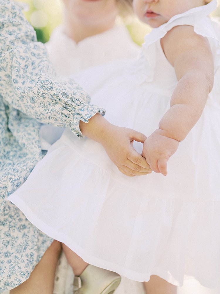 Close-Up View Of A Little Girl Holding Her Baby Sister's Hand.