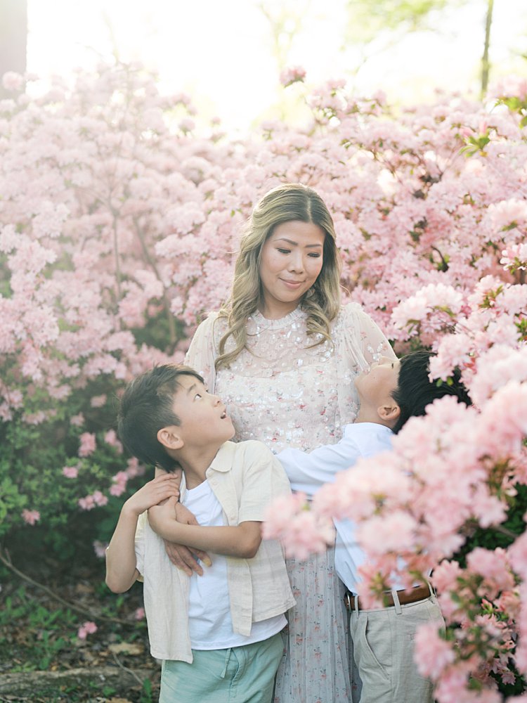 Two Young Boys Look Up At Their Mother While Standing Along Pink Azaleas At Brighton Dam.
