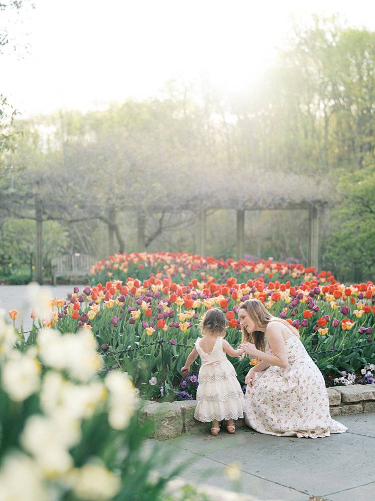 A Mother Crouches Down To Her Toddler Daughter As They Admire The Tulips At Brookside Gardens.