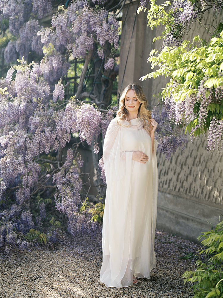 Blonde Pregnant Mother Stands Among Purple Wisteria, Photographed By Georgetown Photographer Marie Elizabeth Photography.