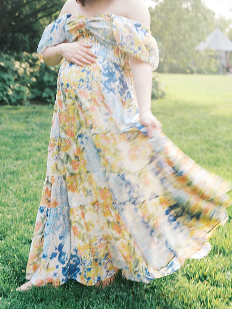 A Blurry Photo Of A Pregnant Woman Swaying Her Orange And Blue Dress During Her Maternity Photos.