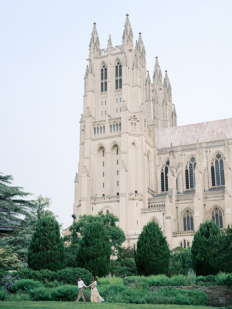 A Couple Walk In Front Of The National Cathedral.