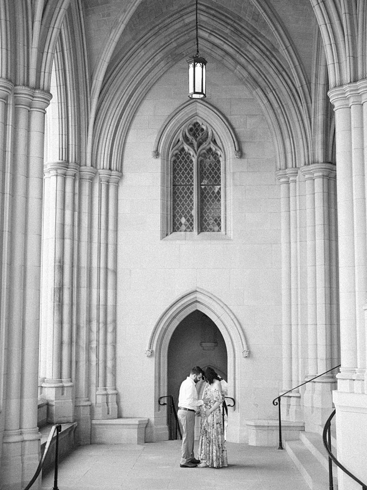 A Couple Stand Together In An Archway At The National Cathedral.