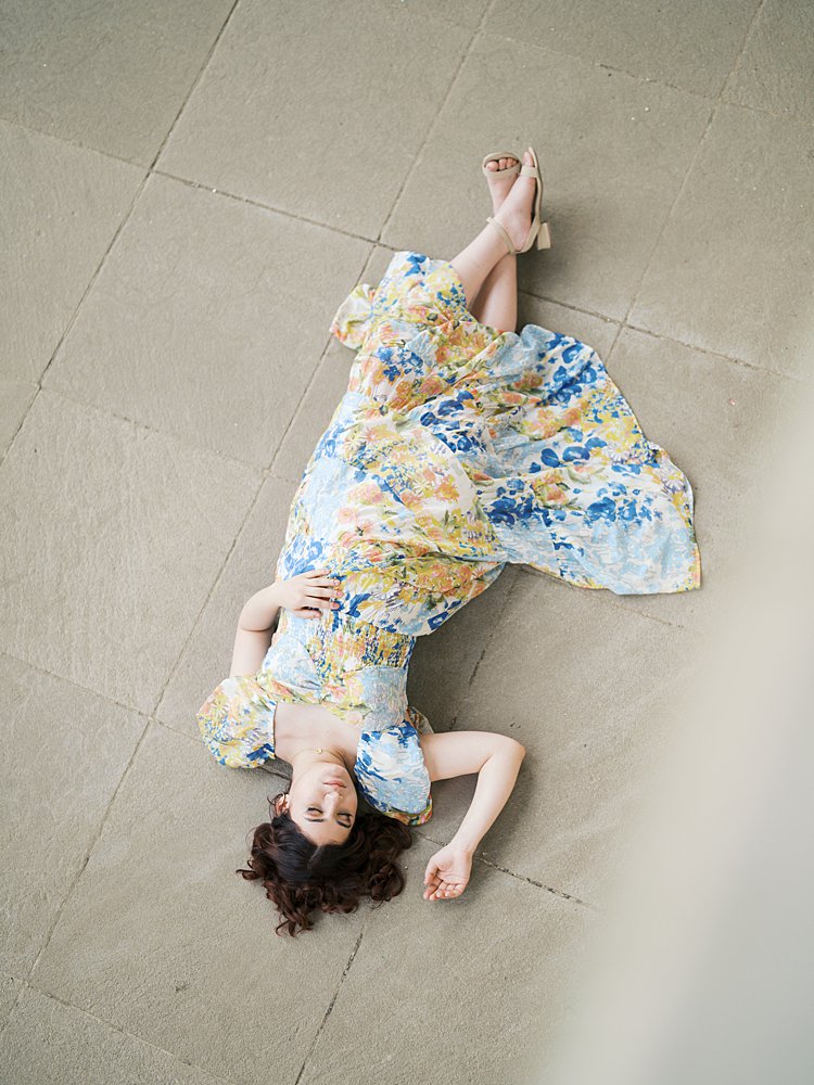 A Pregnant Mother In A Yellow And Blue Dress Lays On The Floor During Her National Cathedral Maternity Session.