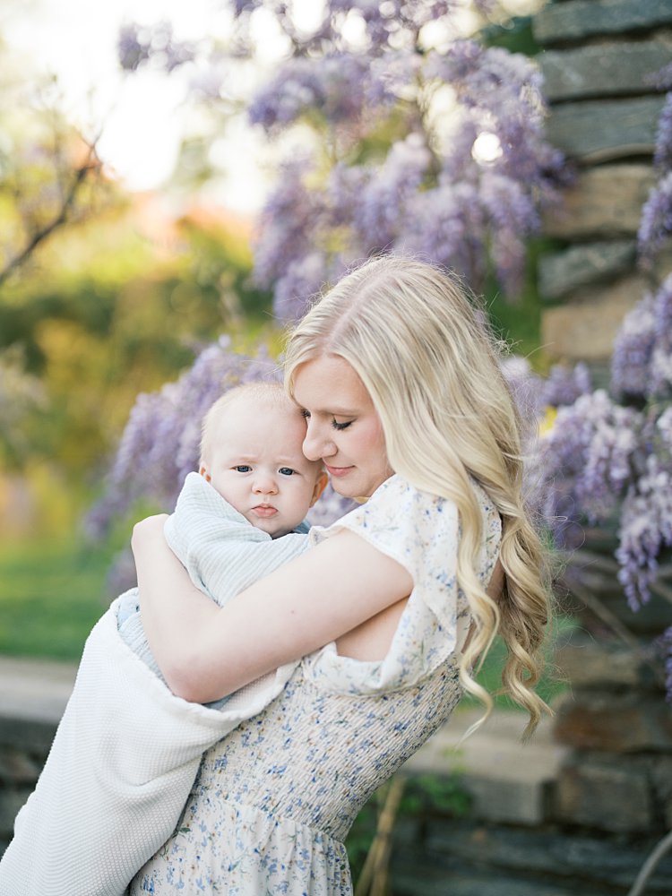 Mother With Long Blonde Hair Holds Her Baby Boy Close To Her While Closing Her Eyes.