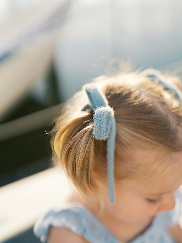 Close-up view of a little girl's pigtail with blue ribbon bow.