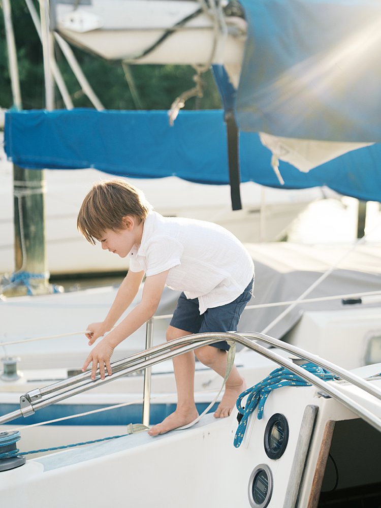 Little boy walks in a sailboat as the sun shines down on him.