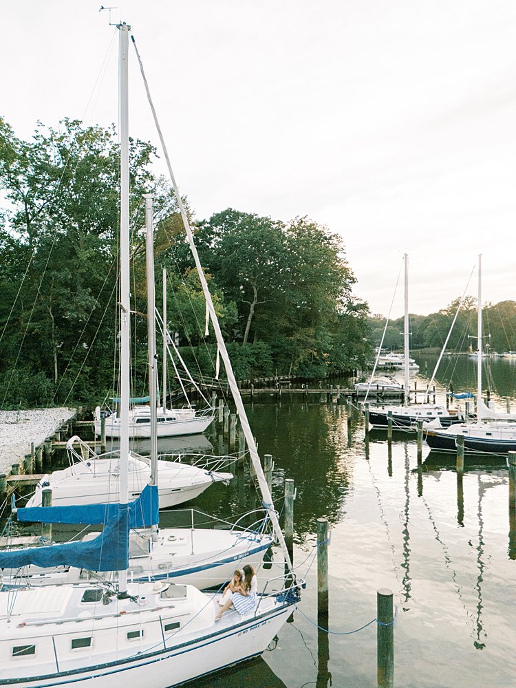 Drone shot of a mother and daughter sitting on a sailboat in the harbor, photographed by Annapolis Family Photographer, Marie Elizabeth Photography.