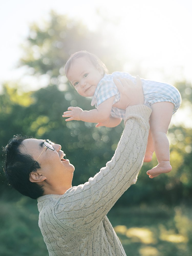 A Father Holds His Baby Boy Up In The Air During Their Mayo Beach Park Photos.