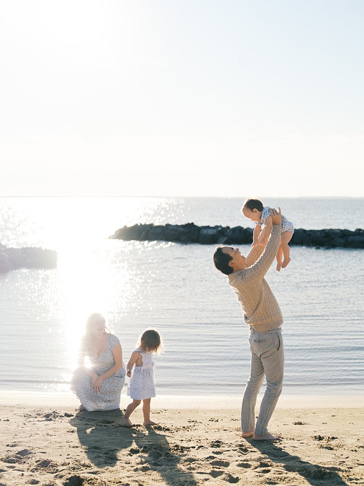A Father Holds His Young Son Up In The Air While A Mother Kneels Down With Her Toddler Daughter During Their Mayo Beach Park Photos.