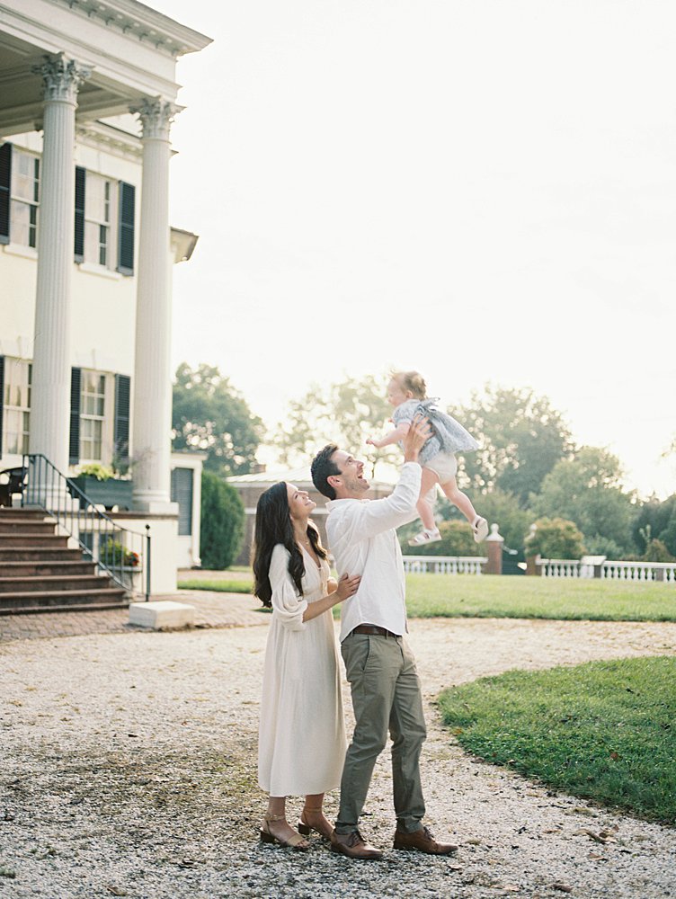 Oatlands VA family photos of a mother and father holding their daughter up in the air.