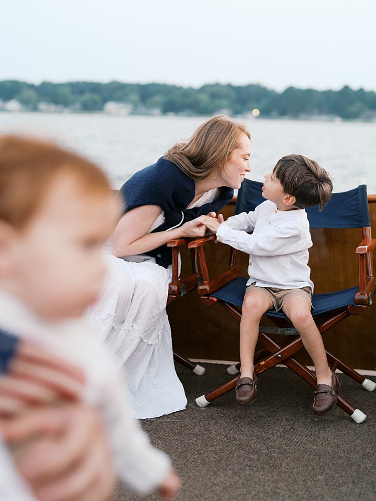 Mother leans down to talk to her young son a sailboat during their family photos.