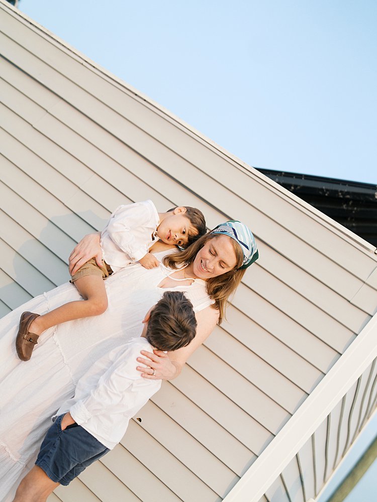 Sideways view of mother with her two young sons against a building.