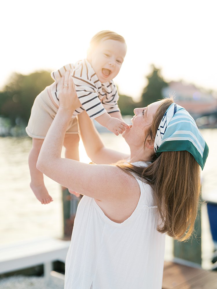 Red-haired mother holds her baby up in the air during their family photo session in St. Michael's, MD.