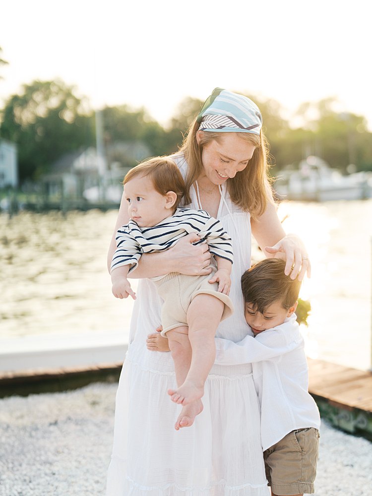 Red-haired mother strokes her young son's hair as they stand along dock in St. Michael's.